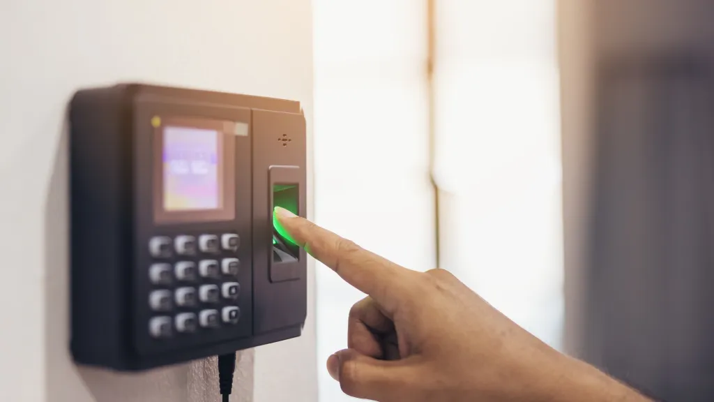 Worker pressing a finger on a wall-mounted time clock to punch out