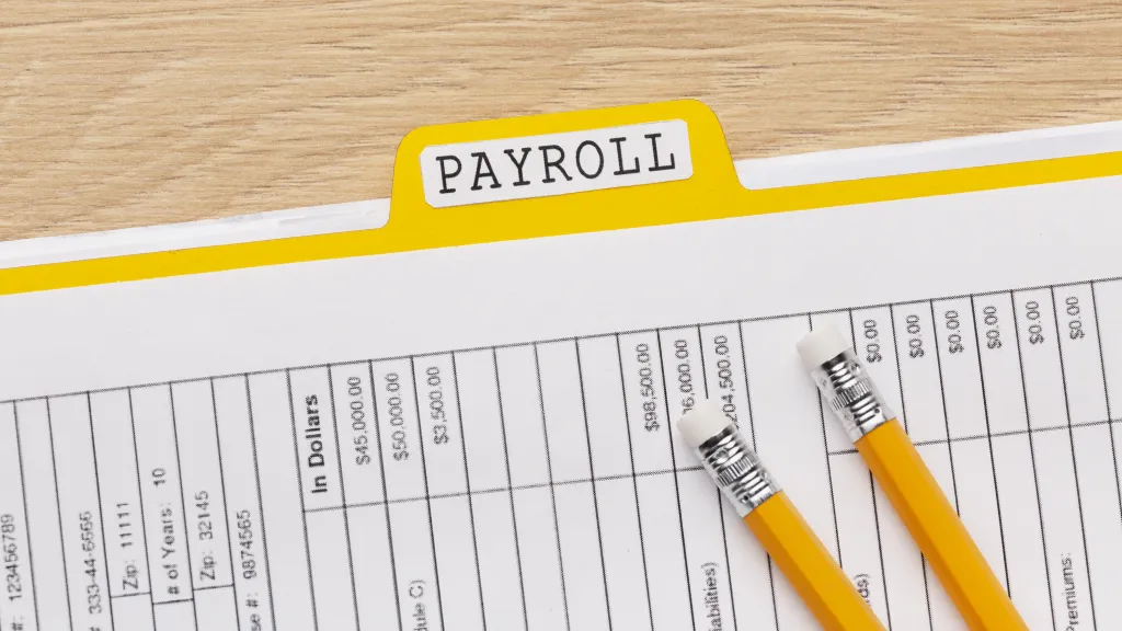 Payroll folder and a ledger of pay amounts with two pencils