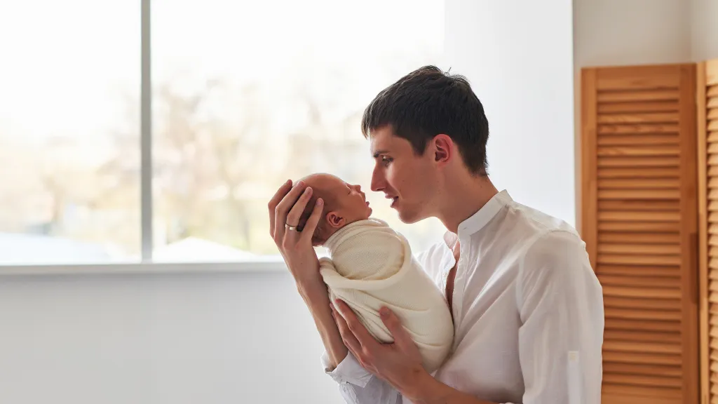 Father holding his newborn baby at home