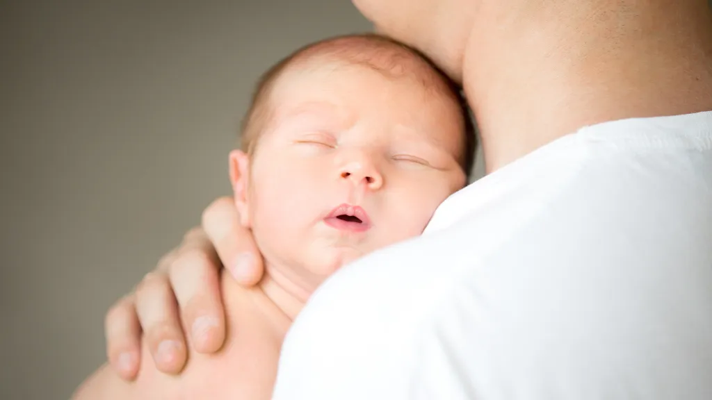Newborn asleep on a parent's shoulder