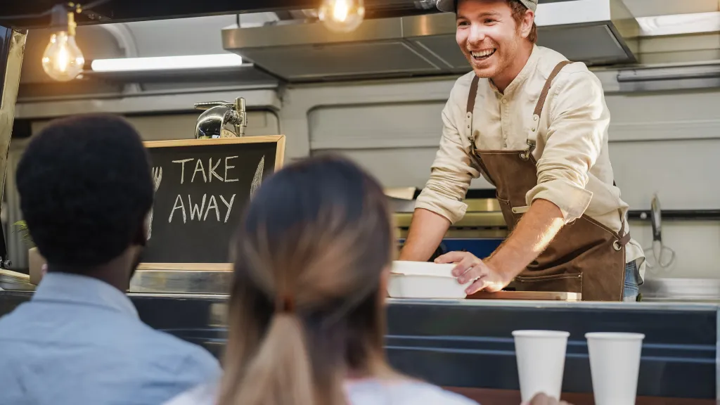 Food truck worker serving a takeaway order to customers