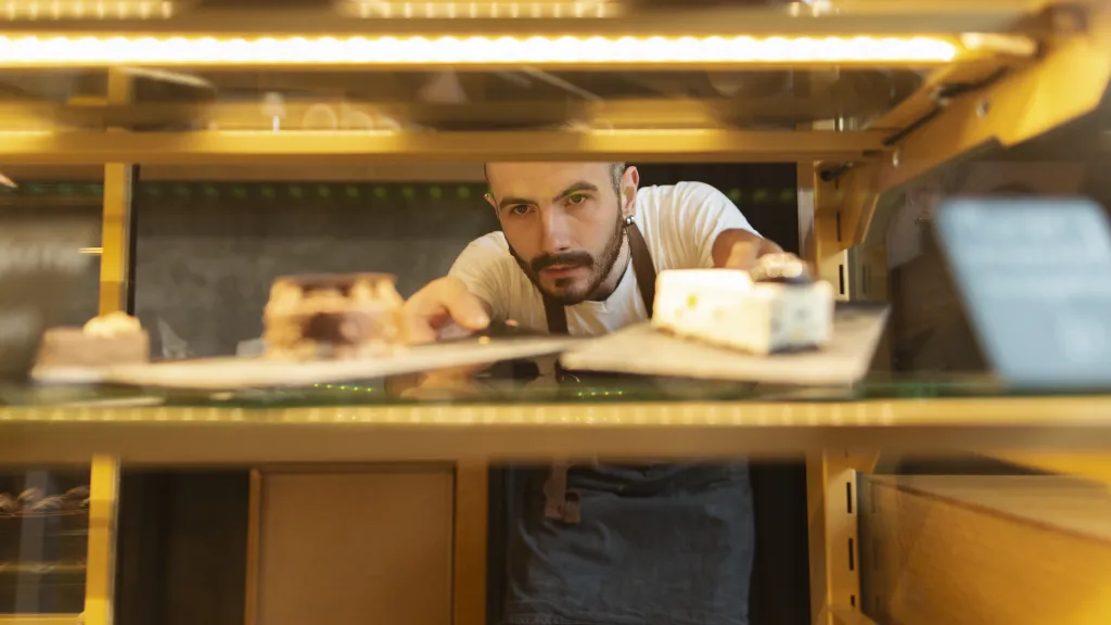 Bakery worker arranging pastries in a display case