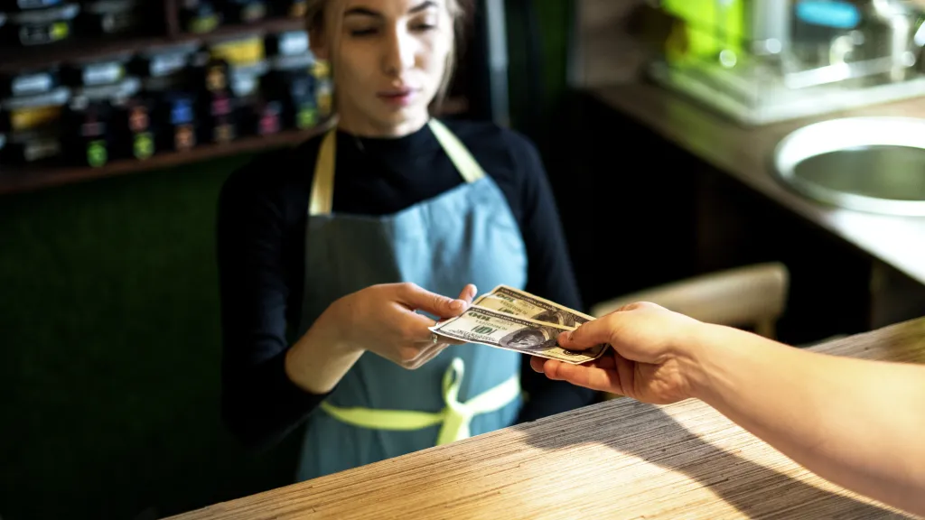 Customer handing cash to a waitress at a cafe counter